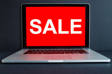 Laptop monitor screen and sale label on a bright red background front view. The concept of online shopping