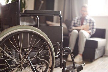 Man reading book, wheelchair in front of him - Powered by Adobe