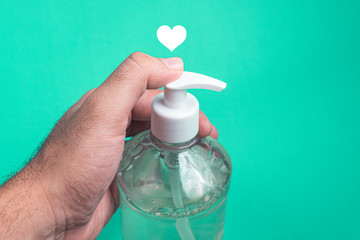 Man hand in container with alcohol gel on the light blue background