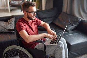 Fototapeta na wymiar Man in wheelchair using laptop on his knees