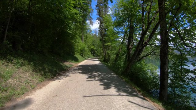 Lake Bled empty promenade asphalt road, Slovenia. Beautiful and warm spring day. Covid-19 lockdown quarantine. No tourists walking around lake. Wide shot, forward dolly moving