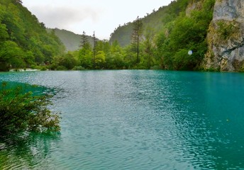 Imagen primaveral de pasarelas flotantes de madera junto a cascadas y lagos azules con antiguos...