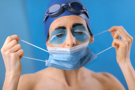 Female swimmer wearing protective face mask because of corona virus pandemic. Portrait of professional sportist with mask. Corona or Covid 19 measure of protection for sports activity.