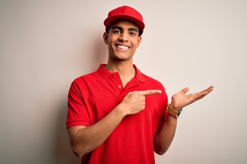 Young handsome african american man wearing casual polo and cap over red background amazed and smiling to the camera while presenting with hand and pointing with finger.