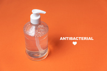 Container with alcohol gel on the orange background