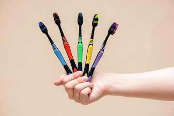 Toothbrushes in female hand close up isolated on light background.