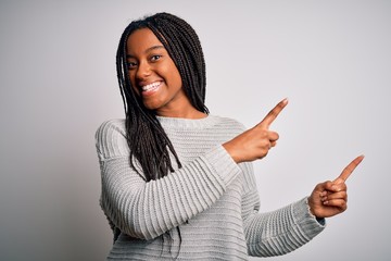 Young african american woman standing casual and cool over grey isolated background smiling and looking at the camera pointing with two hands and fingers to the side.