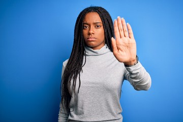Young african american woman standing wearing casual turtleneck over blue isolated background doing...