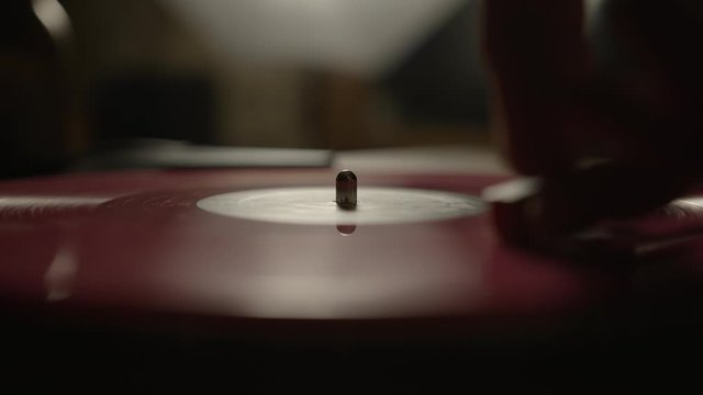 Putting a red vinyl record on turntable and putting stylus needle on