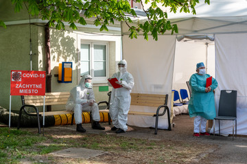 Doctors in protective suits and shields in front of tent waiting