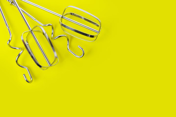 Mixer beaters and dough hooks for stand mixer on yellow background, top view, copy space. Baking concept.
