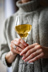 A girl stands by the window with a glass of wine