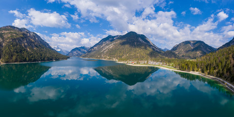 Naklejka na ściany i meble aerial view to wonderful lake plansee in alps landscape with reflections of sky and mountains