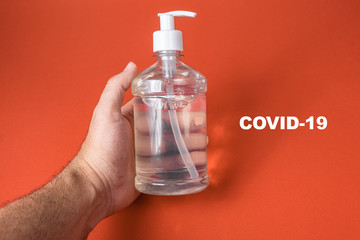 Man hand in container with alcohol gel on the red background