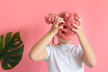 cute blonde boy playing with hand made slime on pink background