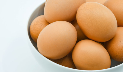 Close up of fresh eggs in a white bowl against a plain white background. Copy space. No people.