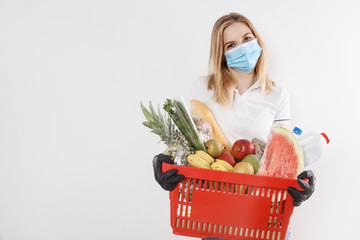 Young woman shopping during a pandemic. Girl in medical mask with basket of products. Shopping times Covid-19