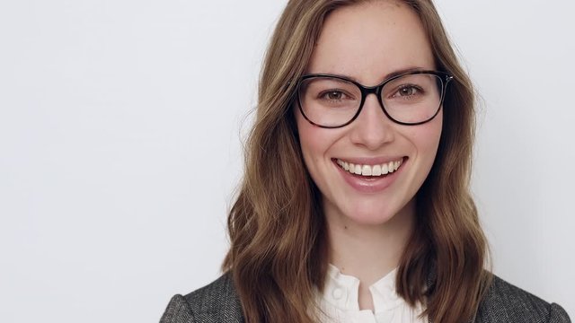 Young businesswoman with glasses being foolish and looking to the left while smiling and being cheerful 