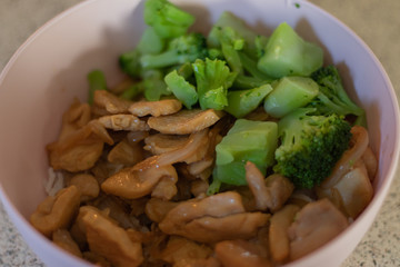 Cooked teriyaki chicken, steamed rice and broccoli in a pink bowl.