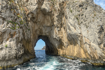 Fototapeta na wymiar The arched tunnel in the Faraglioni rock formation off the coast of Capri.