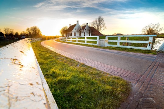 Closeup Shot Of A Curb And A Road Leading To White House With Brown Roof