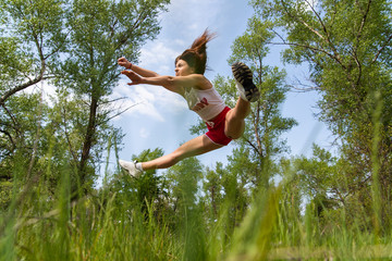 Young athletic girl doing an acrobatic stunt in the air. Jump Twine. Doing sport outside
