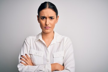 Young beautiful brunette woman wearing casual shirt over isolated white background skeptic and...