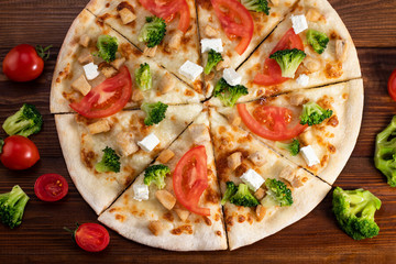 Fototapety  Pizza z kurczakiem, brokułami i serem feta na drewnianym tle. Widok z góry