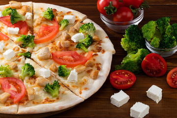 Pizza with chicken, broccoli and feta cheese on wooden background