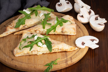 calzone with fresh arugula and mushrooms on a dark background