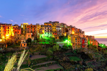 Fototapeta premium Evening panorama of the medieval town of Cornilla in the Cinque Terre National Park in November, purple sunset and colorful houses in Liguria