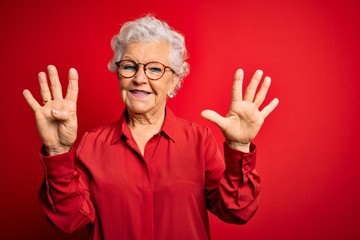 Senior beautiful grey-haired woman wearing casual shirt and glasses over red background showing and pointing up with fingers number nine while smiling confident and happy.