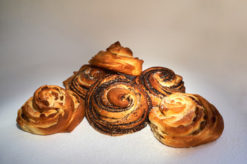 sweet baking pastry buns on a white background sprinkled with poppy seeds