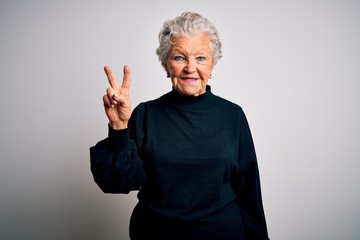 Senior beautiful woman wearing casual black sweater standing over isolated white background showing and pointing up with fingers number two while smiling confident and happy.
