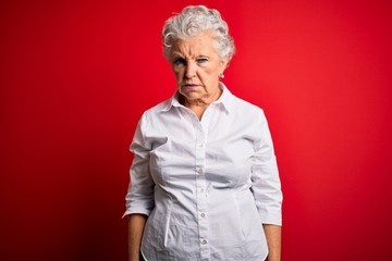 Senior beautiful woman wearing elegant shirt standing over isolated red background depressed and worry for distress, crying angry and afraid. Sad expression.