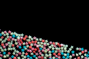 multicolored confectionery sprinkle in the form of stars on a black background