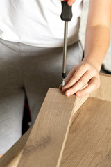 a carpenter screwed a hinge on a wooden board, assembling the cabinet at home