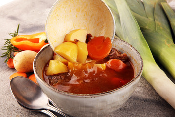 Meat stew with vegetables. Beef stew with potatoes, carrots and fresh herbs on table.
