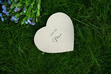 I love you mum written on a heart-shaped card and forget-me-nots on grass