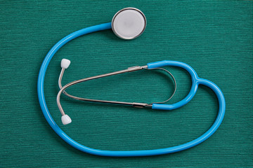 Blue stethoscope on a green background.