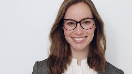 Beautiful young woman trying glasses on and checking how it fits while smiling and being happy - Powered by Adobe