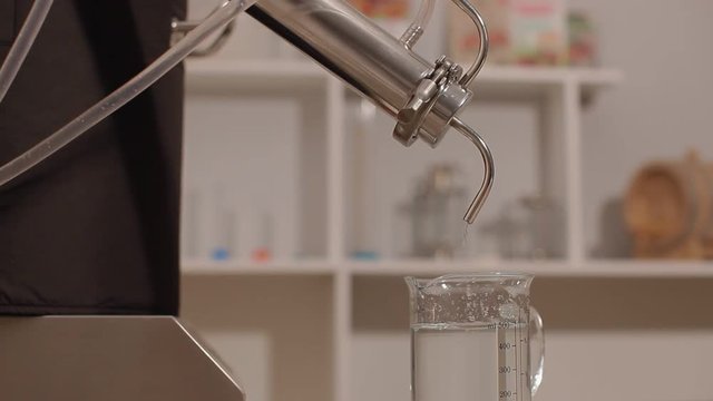 Last step of a Distillery Where Final Product of Alcohol comes out of Spigot for either gin, whiskey, vodka, and rum. Could be used in any industrial video, may be able to superimpose text.