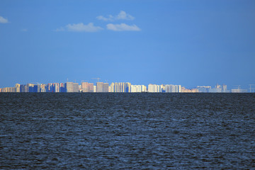 modern high-rise buildings and construction cranes under the blue sky on the seashore