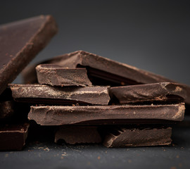 pieces of black chocolate on a black background, sweet dessert