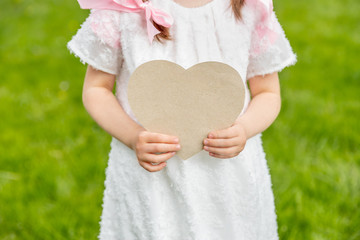 Heart-shaped card held by a girl on a grass background