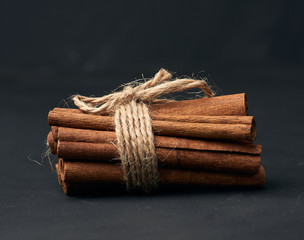 tied bunch of brown cinnamon sticks on a dark background