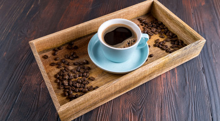 A Cup of coffee and coffee beans in a wooden box on a dark wooden background,top view.