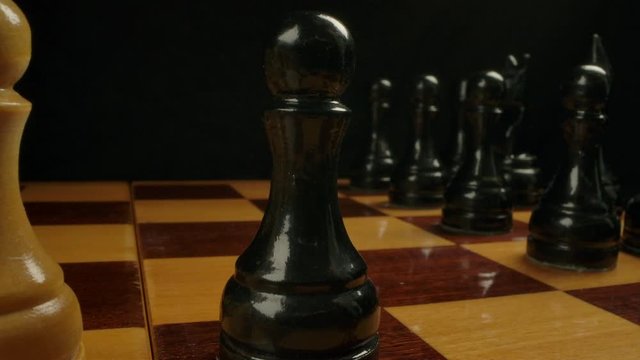 Chess player nominates black central pawn on e5 from e7. Extremely close-up shot of pawn chess piece on checkerboard, wide-angle view of chess game.