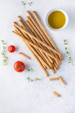 Organic Italian grissini or salted bread sticks and bread lying on a gray background. Fresh Italian snack for apero. Top view, copy space