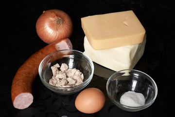 pizza products on black table background cheese butter sausage yeast tomato pepper